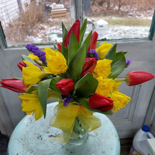 Bouquet of red tulips and yellow daffodils in a clear glass vase