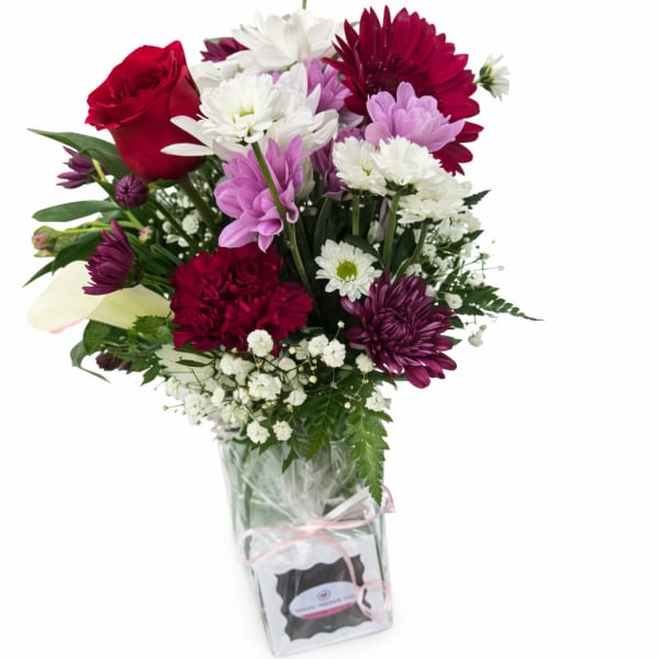 Mixed bouquet of red, white, and purple flowers in a glass vase