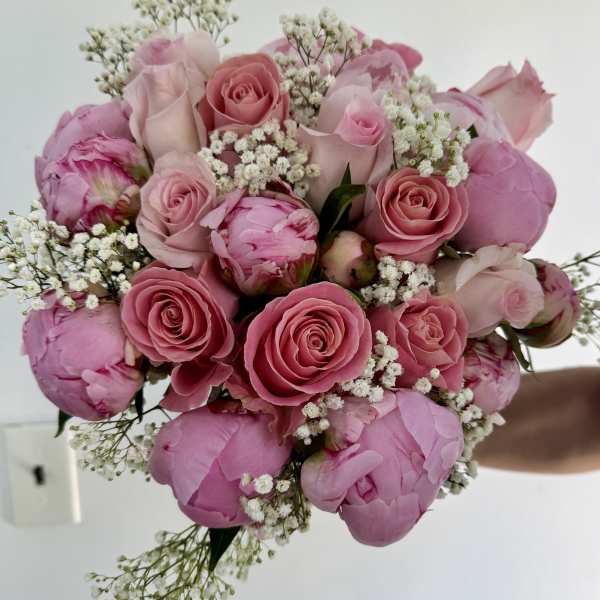 Pink roses and peonies with white baby's breath in a hand-tied bouquet