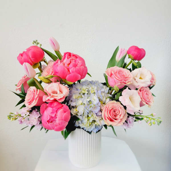 Pink and white floral arrangement in a white ribbed vase