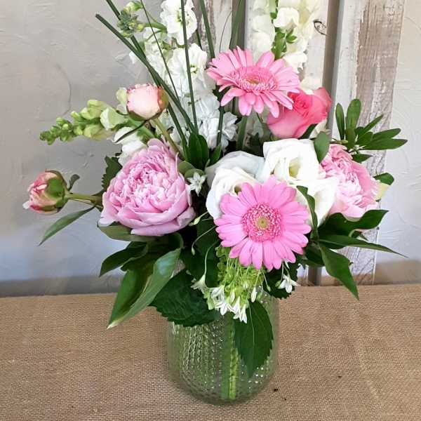 Pink and white flowers arranged in a glass vase