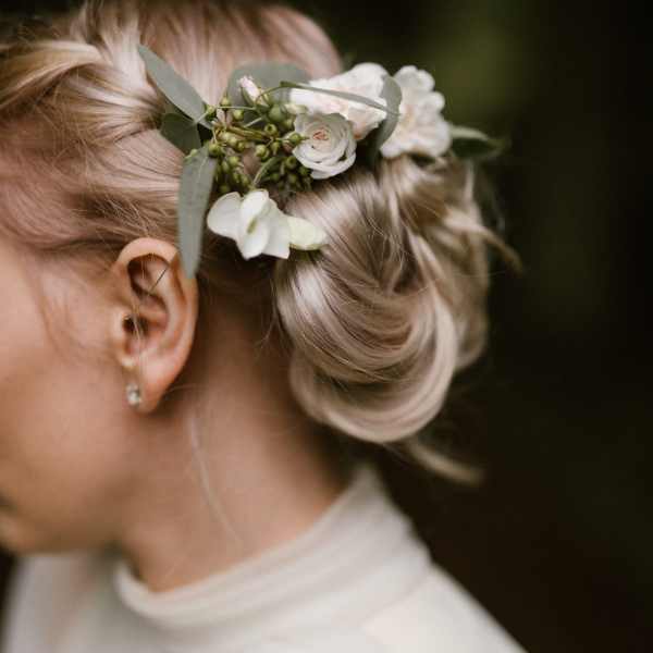 Woman wearing a white floral hairpiece in her blonde updo