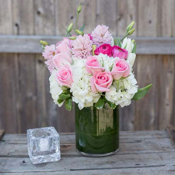 Pink roses and white flowers arranged in a green glass vase