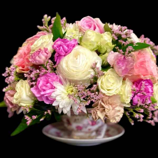 Pink and cream rose bouquet in a teacup on a saucer