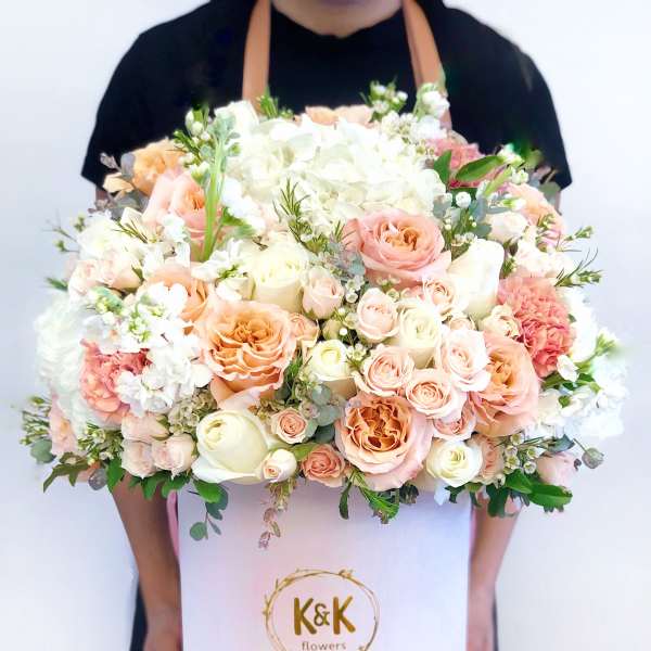 Large pastel bouquet of roses, hydrangeas, and carnations in a white hat box