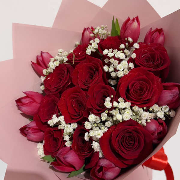 Bouquet of red roses and pink tulips wrapped in blush paper