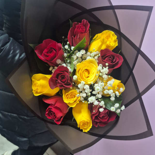 Bouquet of red and yellow roses with white baby's breath in black wrap