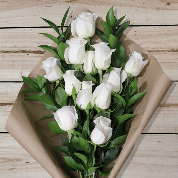 Bouquet of white roses wrapped in brown paper
