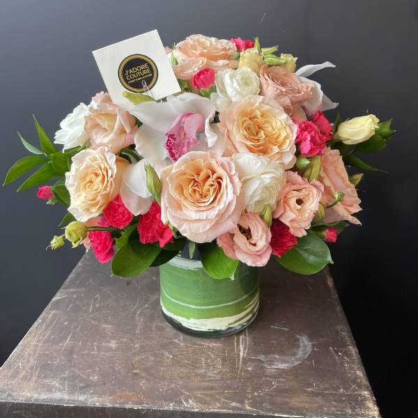 Peach and pink rose bouquet in a green glass vase