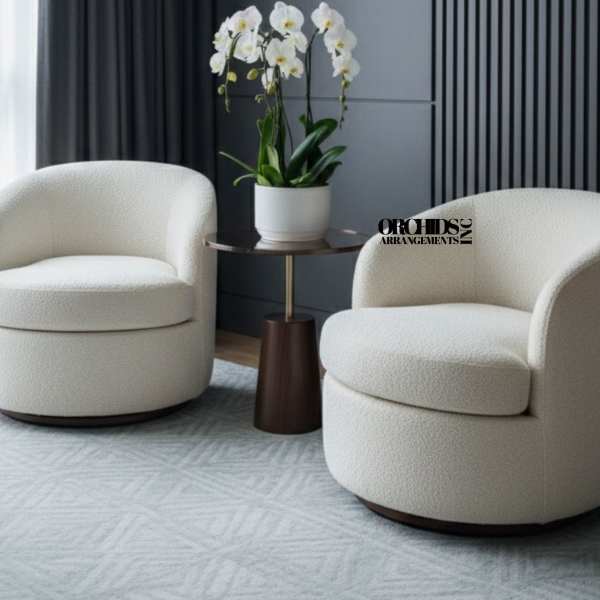 White orchids in a white pot on a small table between two chairs