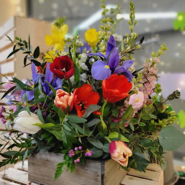 Mixed bouquet of colorful tulips and irises in a wooden box