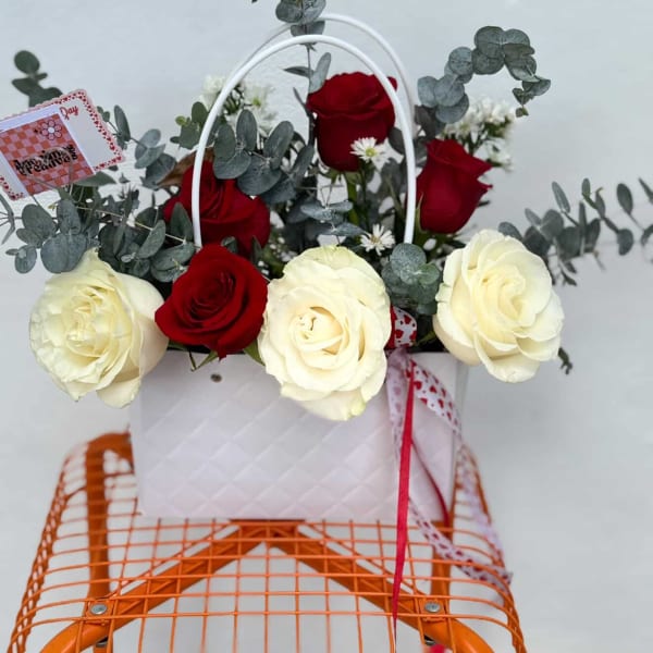 Basket arrangement of red and white roses with eucalyptus and a small card