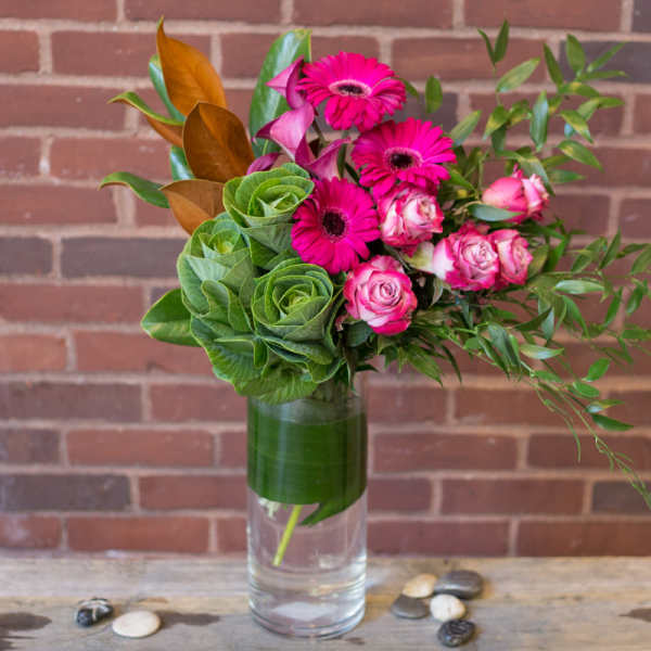 Pink gerbera daisies and roses in a clear glass vase