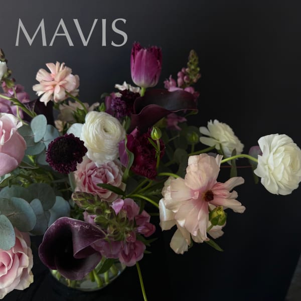 Mixed bouquet with pink, white, and deep purple flowers in a glass vase