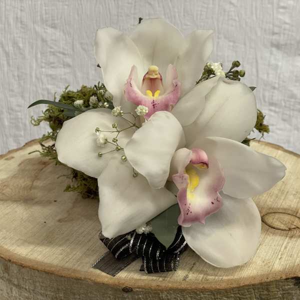 White orchid arrangement with pink centers on a wood slice