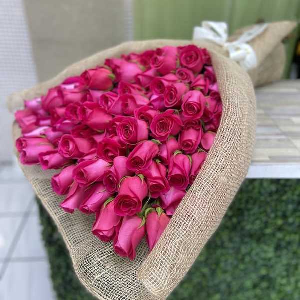 Large bundle of bright pink roses wrapped in natural burlap fabric
