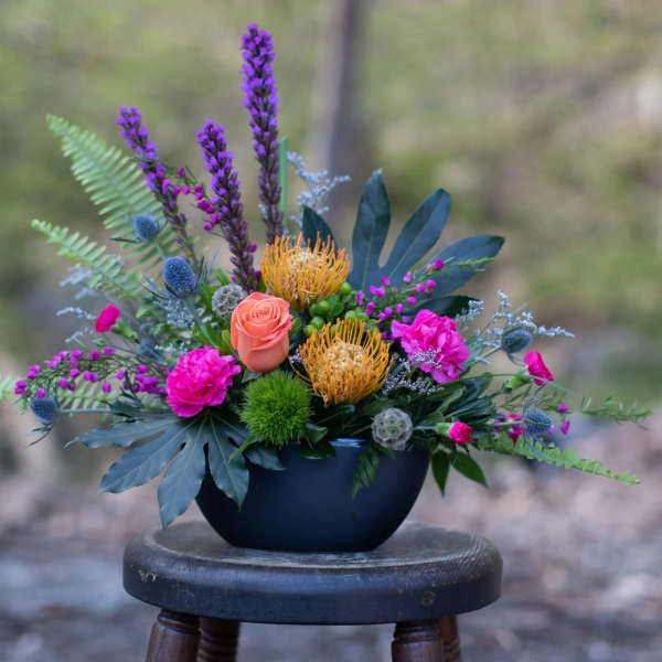 Colorful mixed flower arrangement in a dark bowl vase