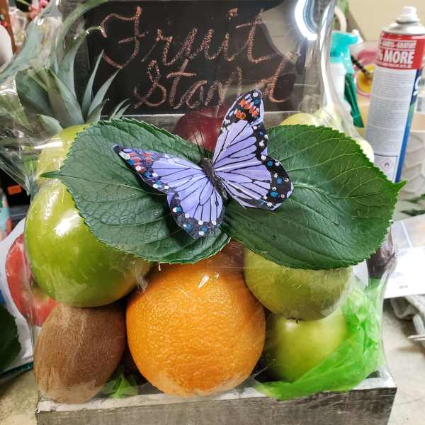 Fruit gift box with apples, orange, kiwi, and a butterfly topper