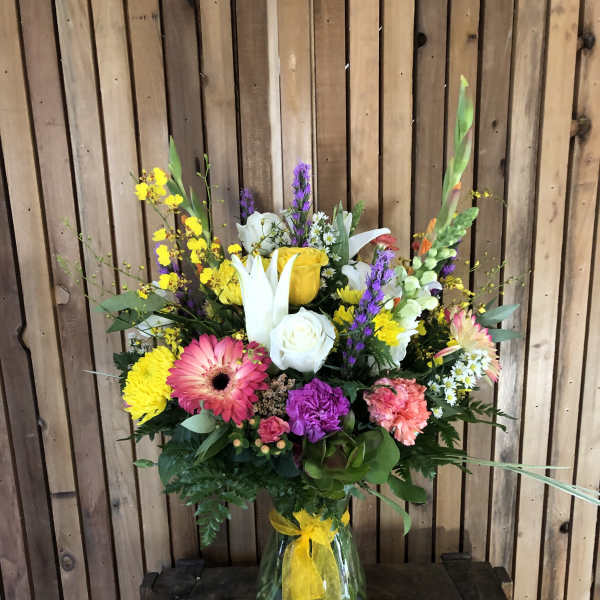 Colorful mixed bouquet in a glass vase with a yellow ribbon
