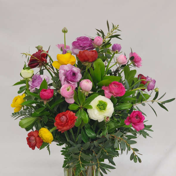 Mixed bouquet of colorful ranunculus in a clear glass vase