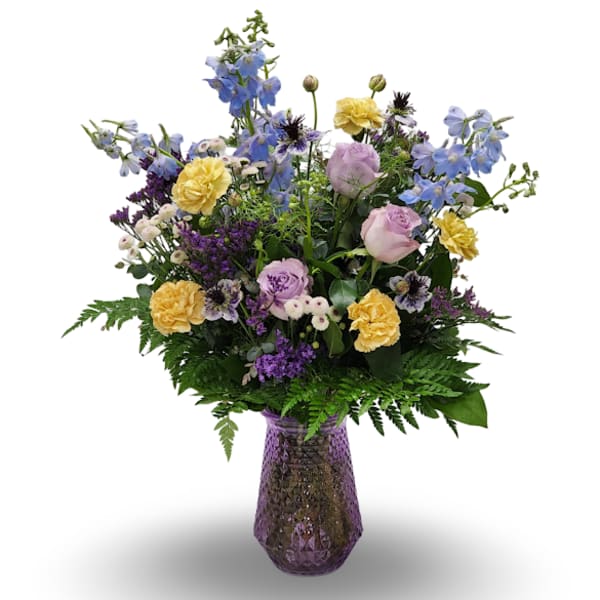 Mixed bouquet of blue, yellow, and lavender flowers in a purple vase.