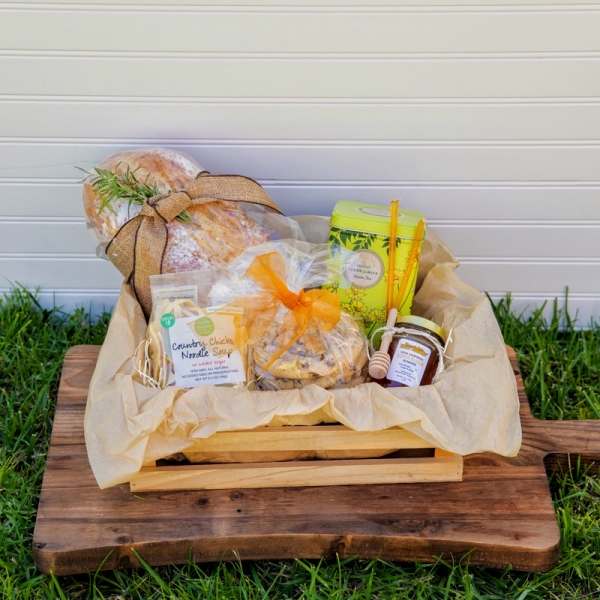 Gift basket with bread, tea, honey, and snacks in a wooden crate