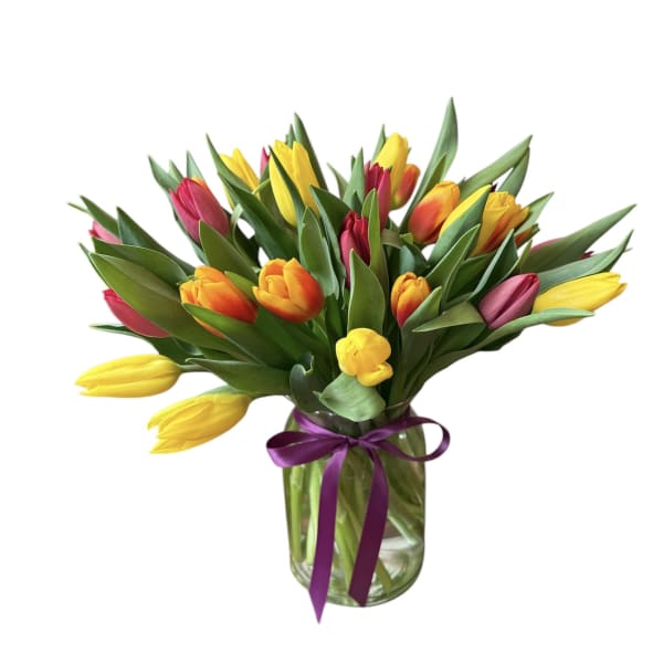 Bouquet of multicolored tulips in a glass vase with a purple ribbon