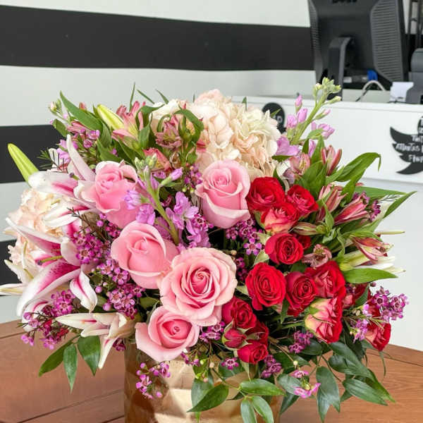 Pink and red roses with lilies in a gold vase