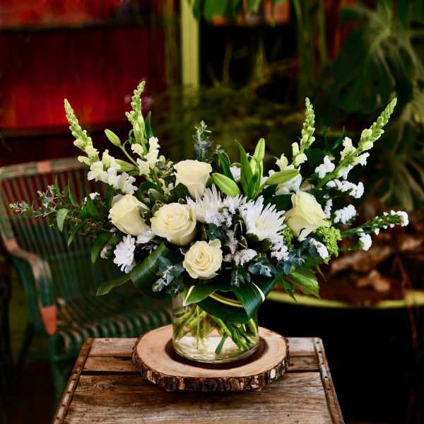 White roses and lilies in a glass vase with white snapdragons and daisies