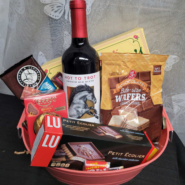 Gift basket with wine and assorted chocolates in a pink container