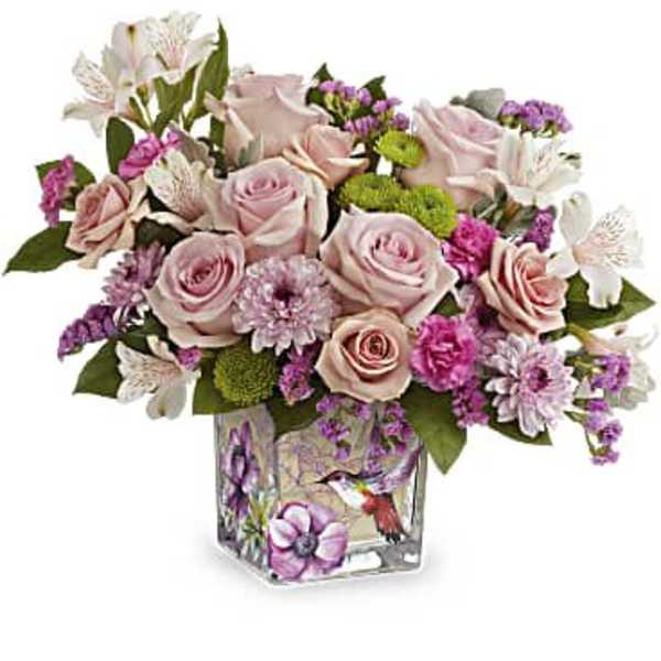 Pink roses and mixed blooms arranged in a square glass vase