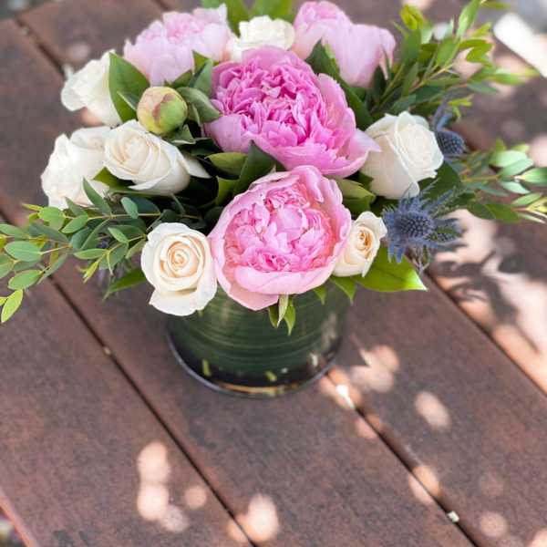 Pink peonies and white roses arranged in a low vase