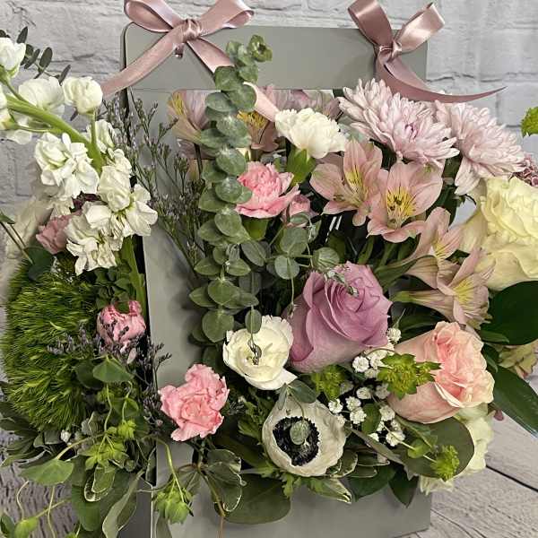 Mixed pastel flower arrangement in a gray gift box with pink ribbons