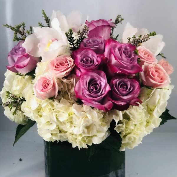Bouquet of pink and purple roses with white hydrangeas in a black vase