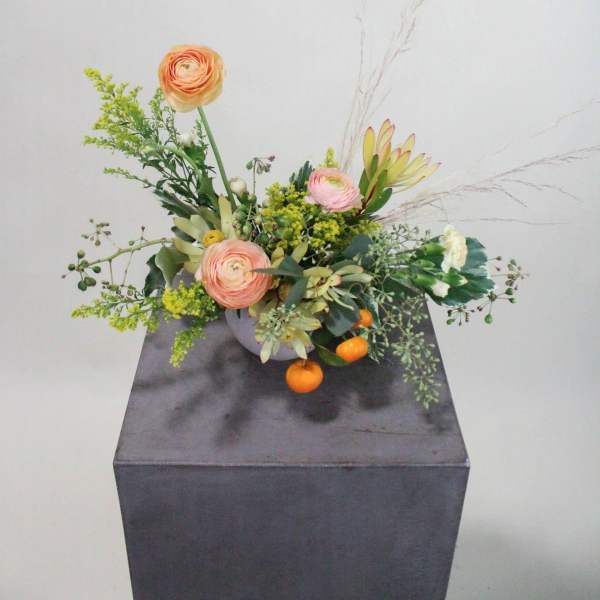 Low floral arrangement with peach blooms in a gray container