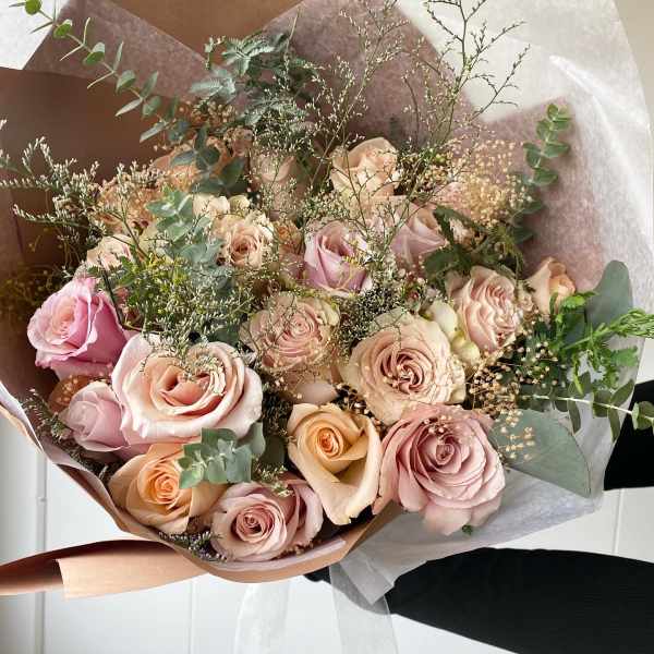 Bouquet of blush and peach roses wrapped in brown and white paper