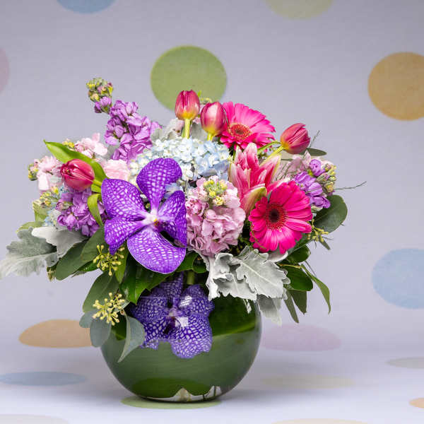 Mixed bouquet of pink, purple, and white flowers in a green vase