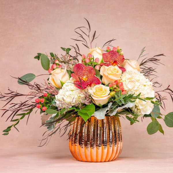 Arrangement of cream roses, white hydrangeas, and red orchids in an orange vase