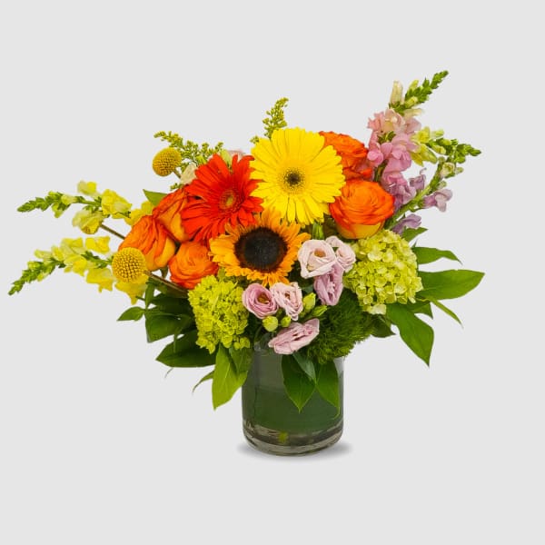 Mixed bouquet of orange, yellow, pink, and purple flowers in a glass vase