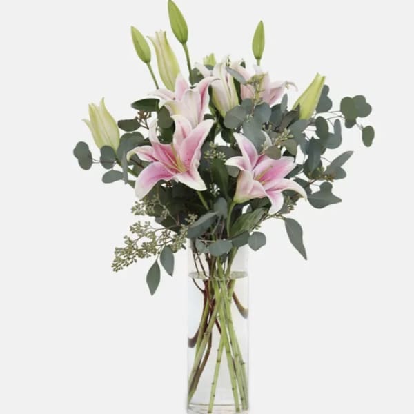 Pink lilies in a clear glass vase with eucalyptus