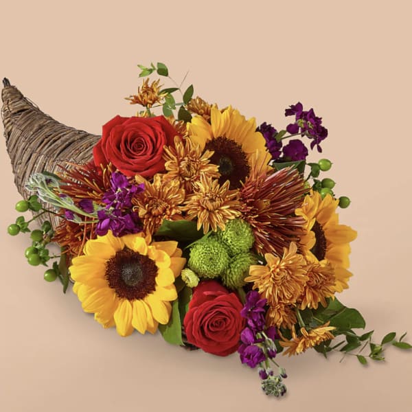 Cornucopia-style bouquet with sunflowers, red roses, and purple blooms