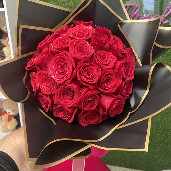 Bouquet of red roses wrapped in black paper with gold trim