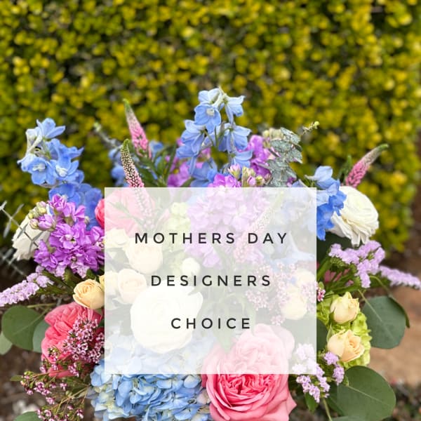 Mixed bouquet of blue, pink, purple, and cream flowers in a glass vase