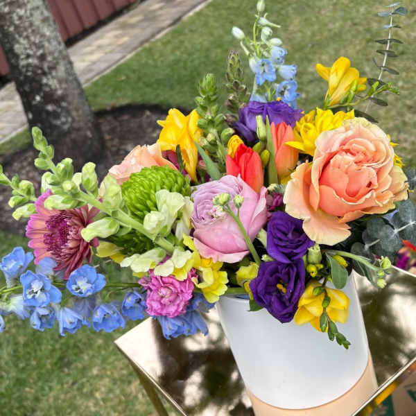 Colorful mixed bouquet in a white vase on a gold stand.