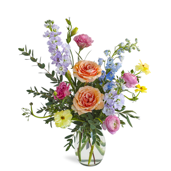 Mixed pastel flower arrangement with peach roses and assorted blooms in a clear glass vase
