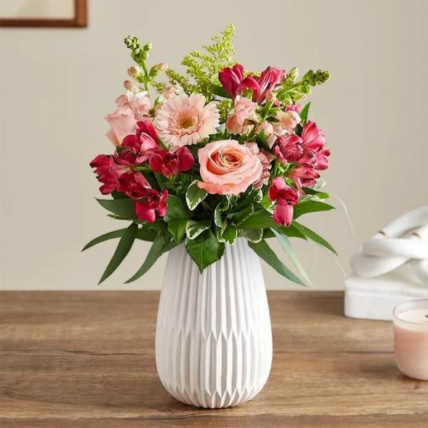 Pink and red mixed flower arrangement in a white vase