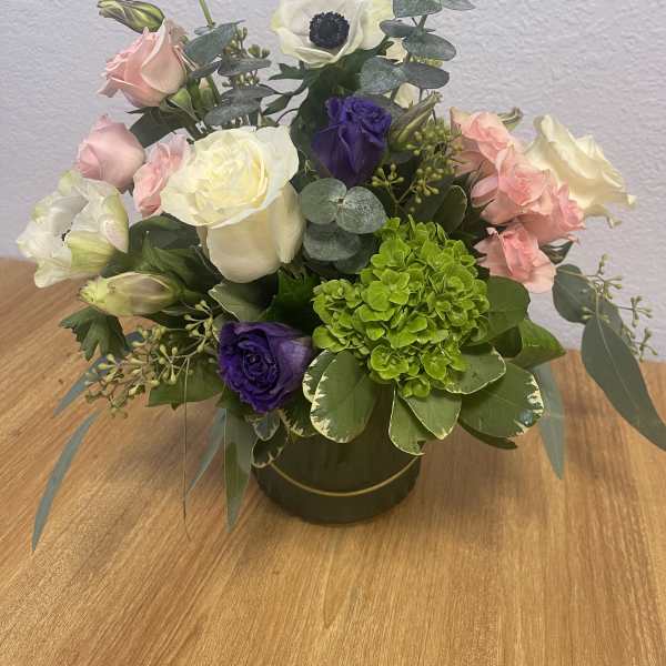 Mixed bouquet of pink, white, purple, and green flowers in a round vase