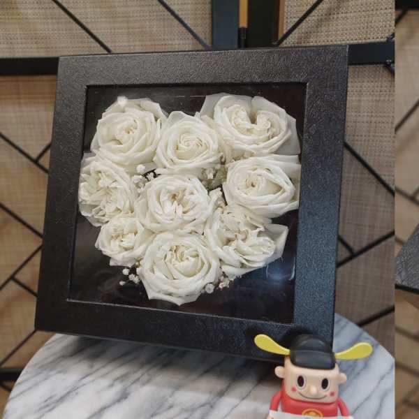 Black square boxes filled with white roses arranged in heart shapes