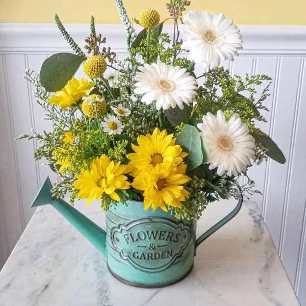 Yellow and white flowers arranged in a turquoise watering can