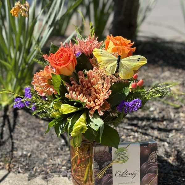 Mixed bouquet in a vase with a box of chocolates beside it